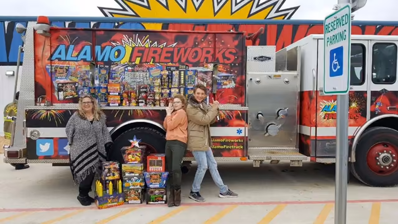 Customers posing with their fireworks in front of the Alamo Fireworks fire truck